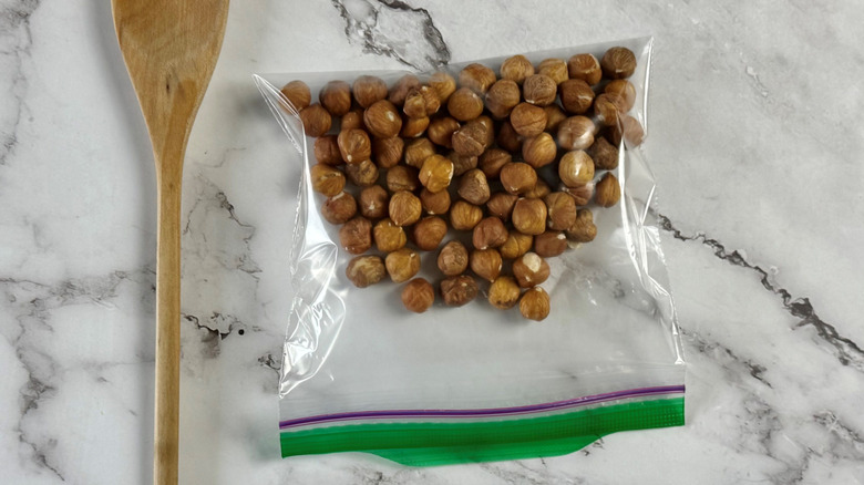 Hazelnuts in plastic baggie next to wooden spoon
