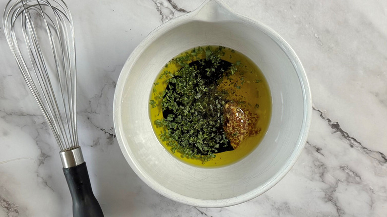 Vinaigrette ingredients in bowl next to whisk