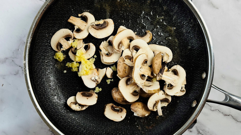 uncooked mushrooms and minced garlic in frying pan