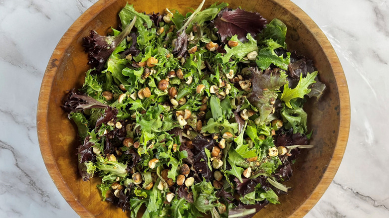 Mixed greens with hazelnuts in wooden salad bowl