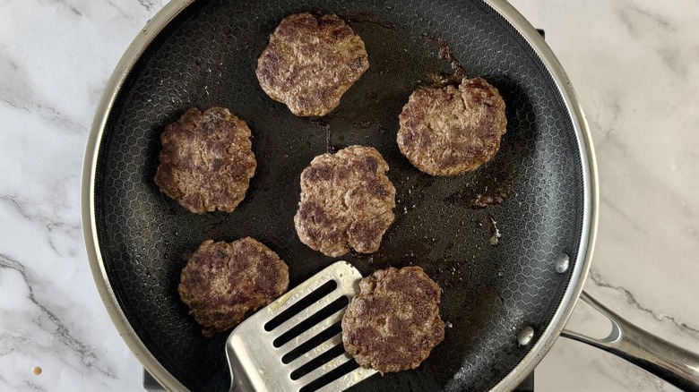 cooked ground beef patties in frying pan