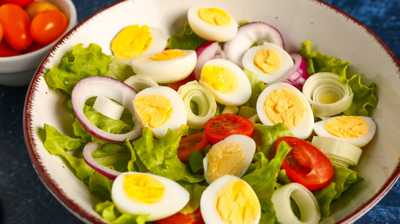 White bowl with mixed salad and quail eggs