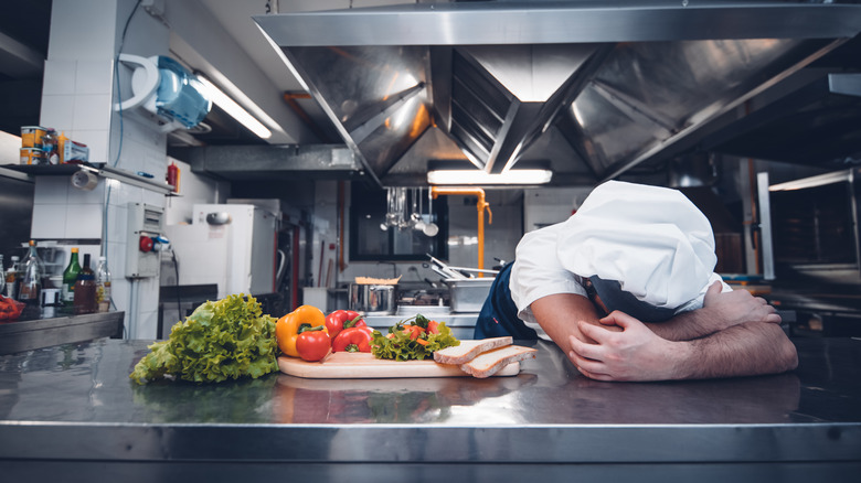 Chef laying on kitchen counter with vegetables