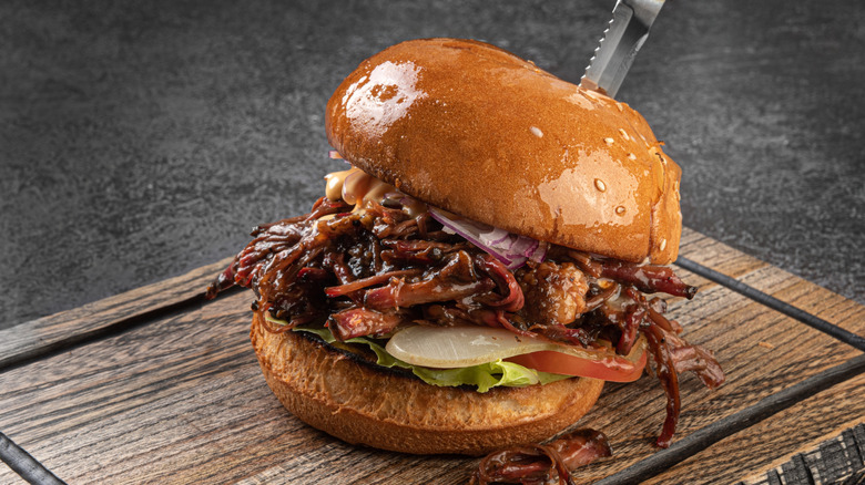 A pulled pork burger on a wooden tray