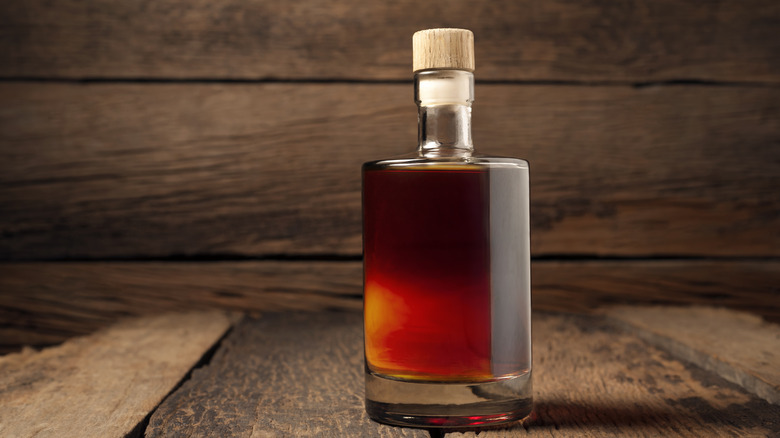 Close-up of whiskey bottle on wooden table against wooden wall