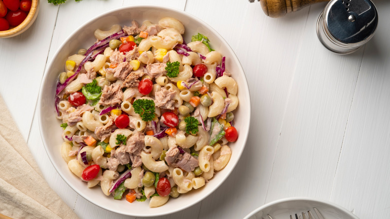 A full bowl of pasta salad with tomatoes, corn, purple cabbage, tuna, and a creamy dressing