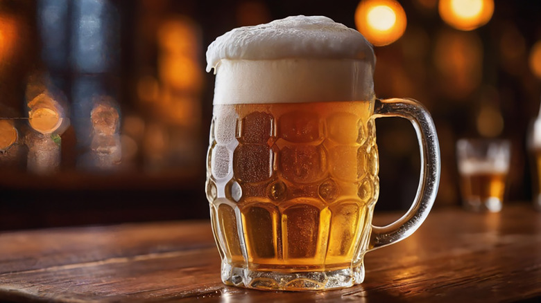 Glass beer mug with light beer at the bottom and a foam head on top.