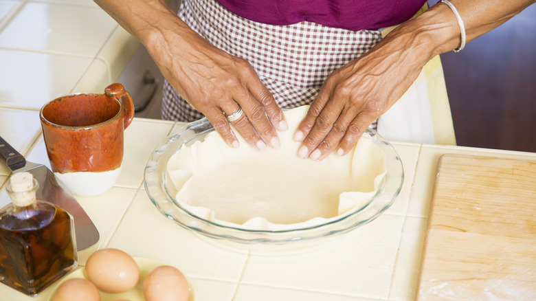 A woman crimps the crust of a pie