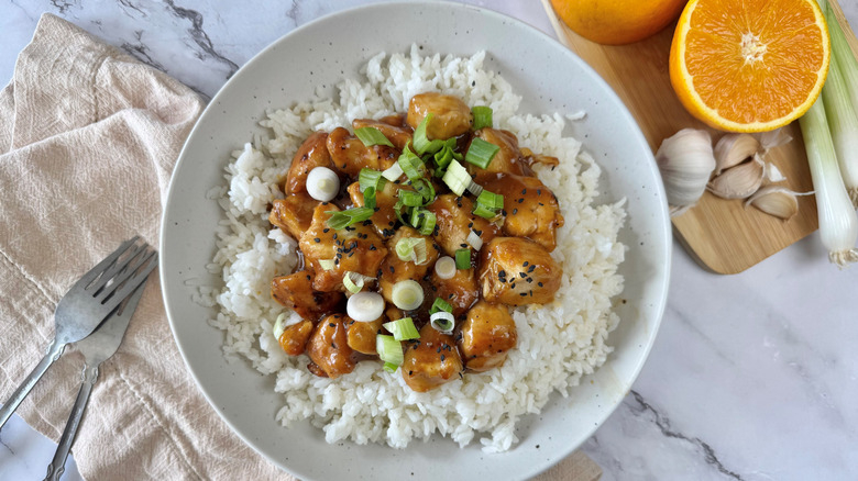 orange chicken with rice and scallions in bowl