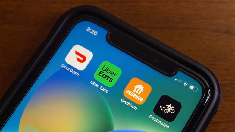 A phone screen shows four food delivery apps