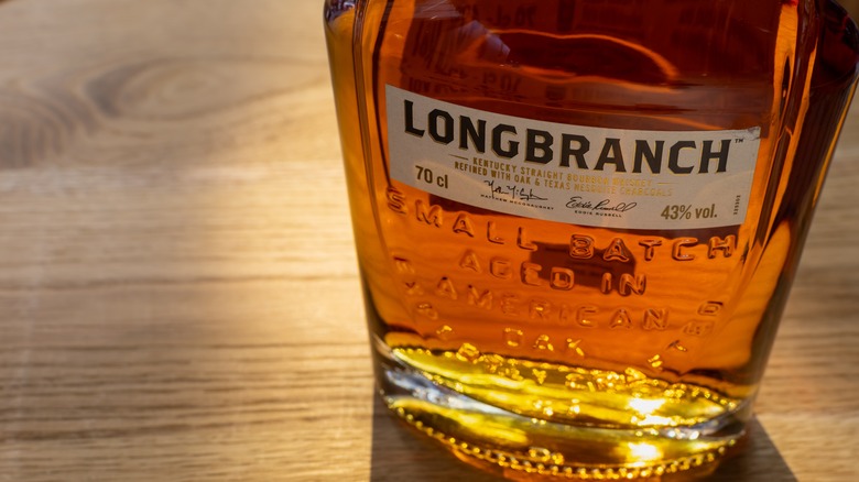 Bottle of Longbranch bourbon sitting on wooden surface