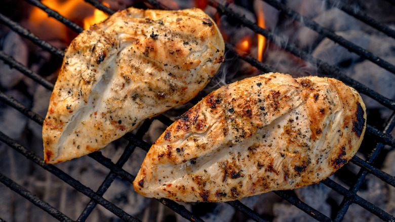 two chicken breasts sit on a grill